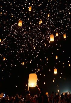 people are flying lanterns in the sky at night with bright lights on them and there is no image to provide a caption for