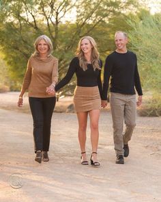 three people walking down a dirt road holding hands