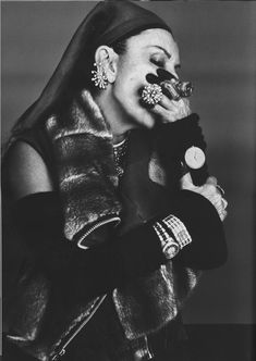 a black and white photo of a woman holding something in her mouth with one hand