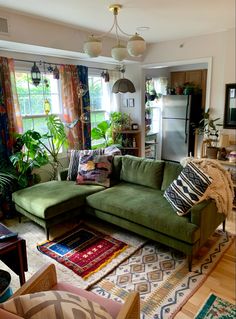 a living room with green couches and rugs in front of a window filled with potted plants