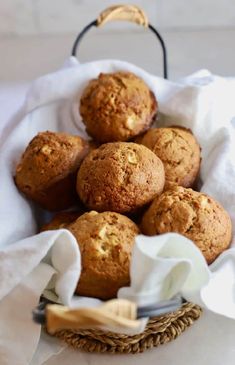 a basket filled with muffins sitting on top of a white cloth covered table