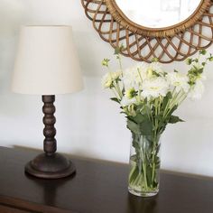 a vase filled with white flowers sitting on top of a table next to a lamp