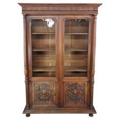 an old wooden bookcase with glass doors and carvings on the front, sitting against a white background