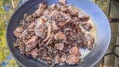 some meat and mushrooms are cooking in a skillet on the stove top burner