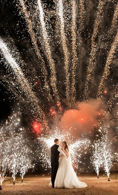 a bride and groom standing in front of fireworks