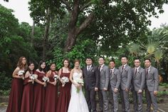 a group of people standing next to each other in front of trees and bushes at a wedding