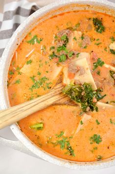 a bowl of soup with meat, vegetables and cheese in it on a checkered table cloth