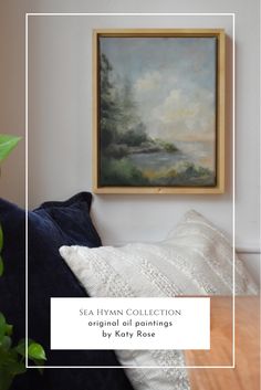 a painting hanging on the wall next to a couch with pillows and a potted plant