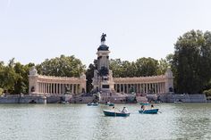 people in small boats on the water near a monument