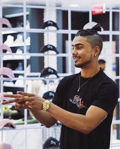 a man standing in front of a wall with hats on it's shelves and holding his hands out