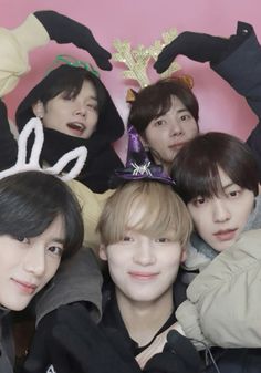 group of young men posing together in front of a pink wall with bunny ears on it