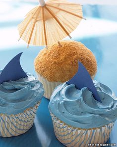 two cupcakes with blue frosting and an umbrella