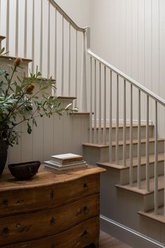 there is a vase with flowers on the table next to the stair case in this room