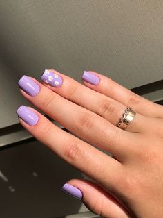 a woman's hand with purple nail polish and white flowers on the ring finger