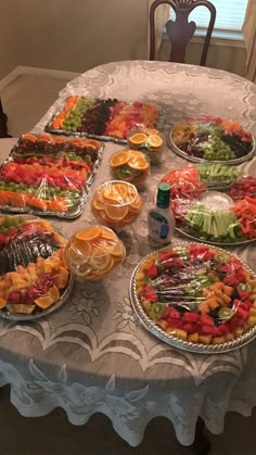 a table topped with trays of food and plates filled with different types of fruit