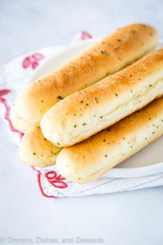 two hot dogs on a white plate next to some bread