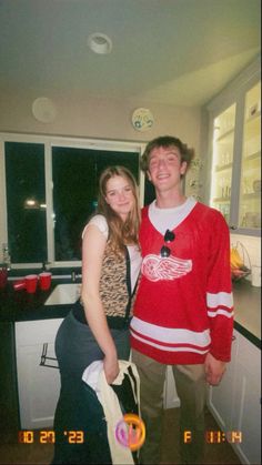 a young man and woman standing next to each other in a kitchen