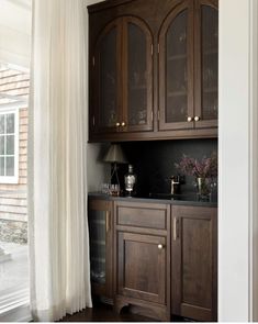 a kitchen with wooden cabinets and white curtains