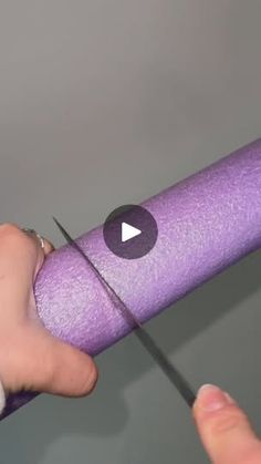 a person is holding a purple object with scissors