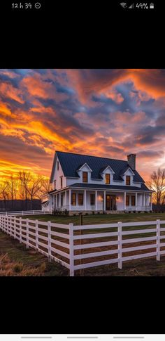 a white house sitting on top of a lush green field next to a fenced in field