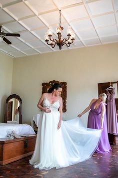 a woman in a wedding dress looking at another woman's gown