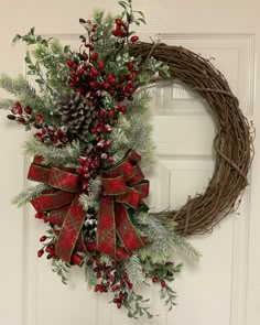 a wreath with pine cones, berries and evergreens is hung on the front door