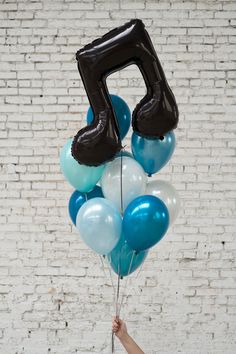 a person holding balloons with the number five on them