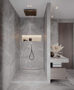 a bathroom with marble walls and flooring, including a shower head in the corner