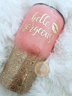 a pink and gold glitter tumbler with the words hello gorgeous on it next to a coin