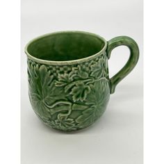 a green ceramic mug with leaves on it