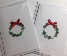 two cards with christmas wreaths on them and red ribbon hanging from the top one