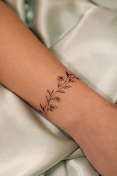 a woman's arm with a flower tattoo on the left side of her wrist