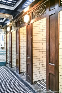 two doors are open on the inside of a public restroom with black and white checkered flooring