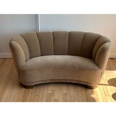 a curved couch sitting on top of a hard wood floor