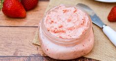 some strawberries are sitting on a table next to a jar of strawberry butter