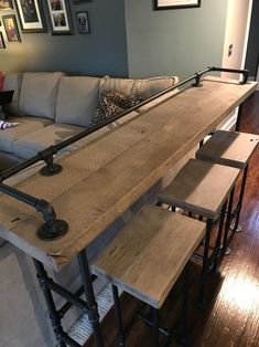 a living room filled with furniture and a wooden table topped with stools next to a couch