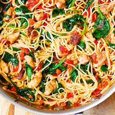 a pan filled with pasta and vegetables on top of a wooden table