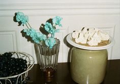 two vases filled with blueberries and flowers on top of a wooden table next to each other