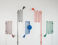 four different colored metal objects hanging on the wall next to each other, with one blue and one red