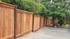 a wooden fence next to a tree filled yard