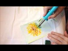 a person is cutting paper with scissors and a flower on the table next to them