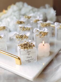 small packages with gold flakes are sitting on a tray next to a lit candle