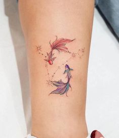 a woman's leg with a tattoo on it that has two goldfishs and stars