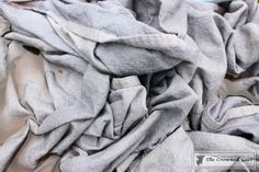 a pile of gray cloth sitting on top of a bed