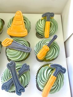 cupcakes decorated with frosting and construction themed icing are in a box