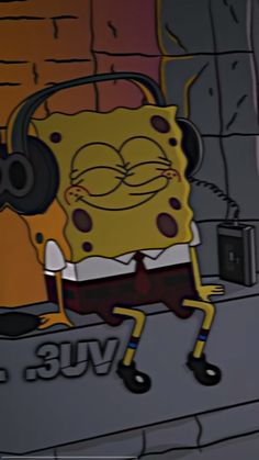 spongebob with headphones on in front of a brick wall, listening to music