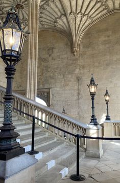 an old fashioned lamp post in the middle of a stone building with stairs and railings