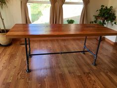 a wooden table sitting on top of a hard wood floor next to a potted plant