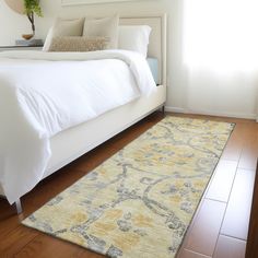 a white bed sitting on top of a hard wood floor next to a large window