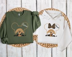 two sweatshirts with mickey mouse ears on them sitting in front of a wicker basket